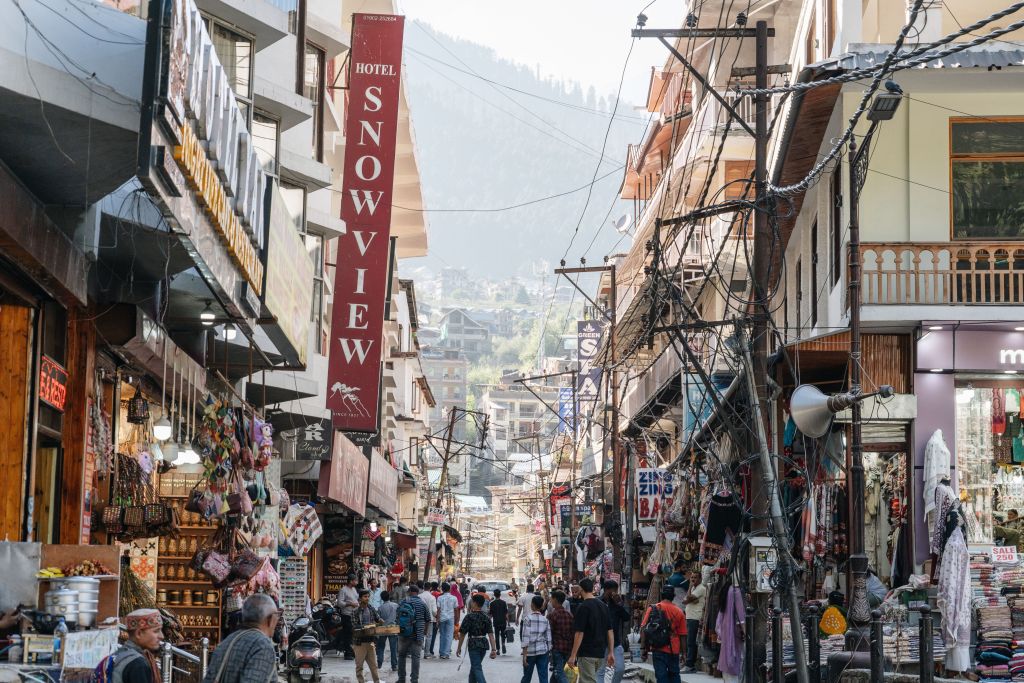 Mall Road Busy market street in Manali town with local shops, Tibetan handicrafts and pine-forested hills in the background