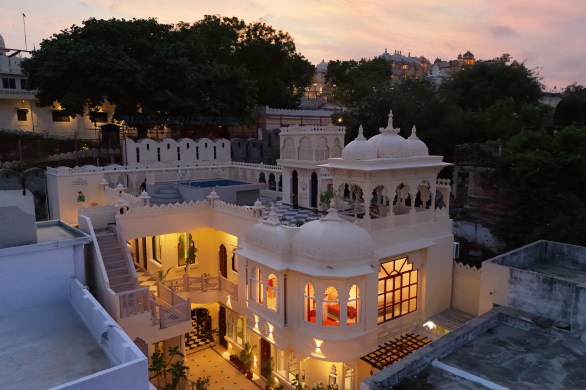 Exterior shot of the Rang Havelii entrance lane at Bhatiyani Chohatta, City Palace boundary wall visible alongside, golden-hour light.