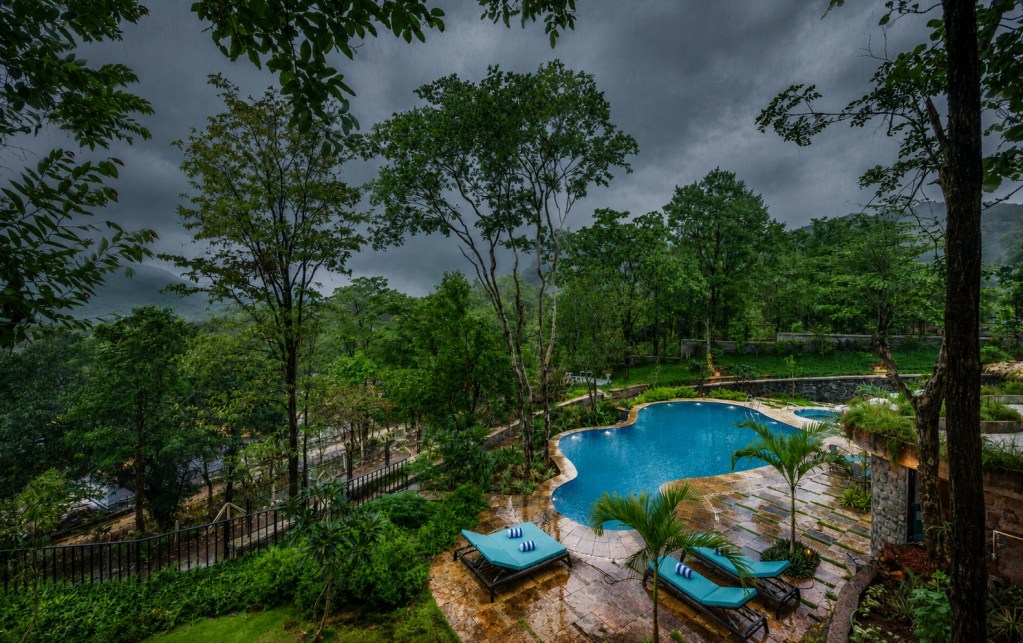 SaffronStays villa pool deck in Khopoli during monsoon rain, Sahyadri hills Maharashtra