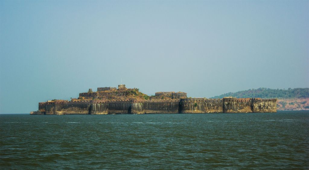 Murud-Janjira Fort surrounded by open sea, shot from a circling boat with monsoon clouds overhead.