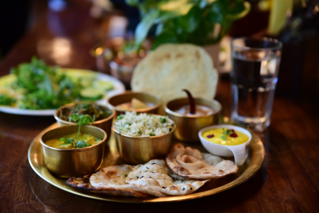 Home-cooked thali spread on a wooden table inside a private villa during monsoon
