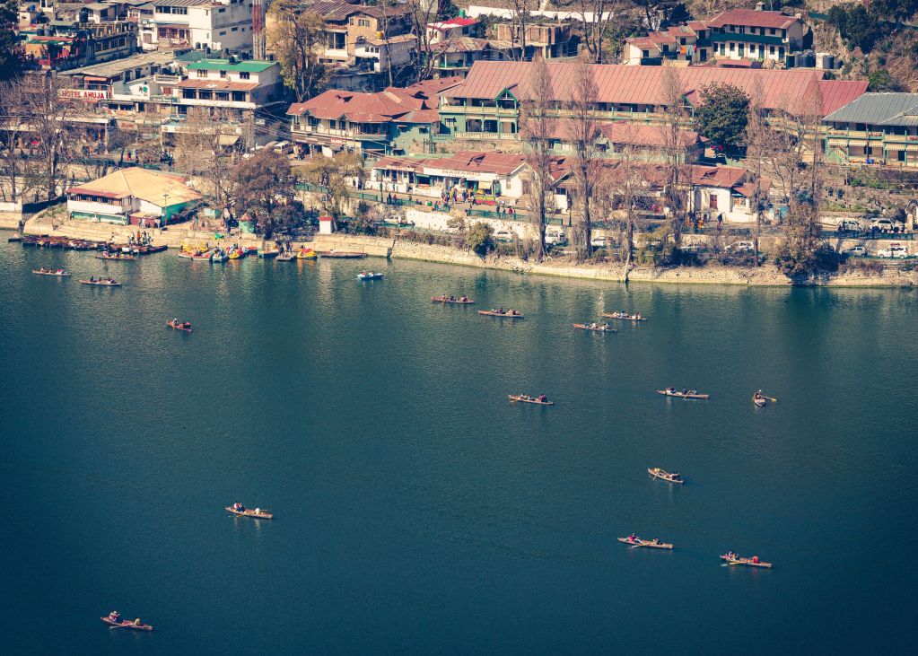 Aerial view of a serene lake surrounded by buildings, with several boats floating on the water.